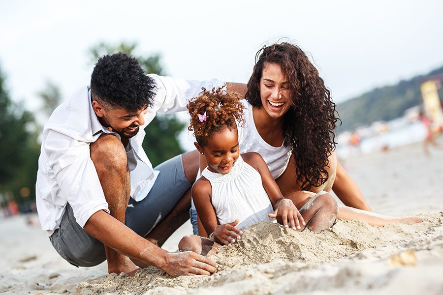 Personal Insurance - Happy Parents Playing on the Beach with Their Young Daughter